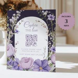 Pode incluir: Um sinal de casamento floral roxo e branco com um código QR que diz "Capture the love" e "Por favor, compartilhe suas fotos conosco. Basta escanear e enviar". O sinal também diz "Inclui 3 tamanhos".