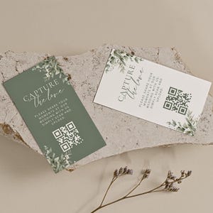 May include: Two green and white cards with a floral design and a QR code. The text on the cards reads "Capture the love" and "Please share your moments at our wedding with us. Simply scan and upload."
