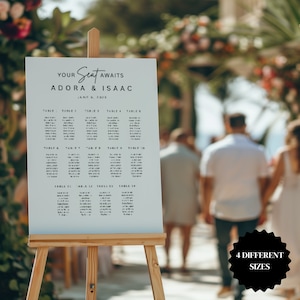Op de afbeelding: Een wit huwelijkszitplan met de tekst "YOUR Seat AWAITS ADORA & ISAAC JUNE 6, 2025" bovenaan. Het plan vermeldt tafels 1 tot en met 14 met de namen van de gasten.