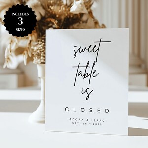 Puede incluir: Un letrero blanco con texto negro que dice "sweet table is CLOSED". El letrero también incluye los nombres "ADORA & ISAAC" y la fecha "MAY, 16th 2025". Un círculo negro con las palabras "INCLUDES 3 SIZES" está en la esquina superior izquierda.