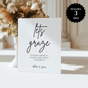 Könnte beinhalten: Ein weißes rechteckiges Schild mit den Worten "lets graze" in eleganter schwarzer Schrift. Darunter steht "PLEASE GRAB A PLATE AND HELP YOURSELF" und "adora & isaac". Ein schwarzer Kreis mit "INCLUDES 3 SIZES" befindet sich oben rechts.