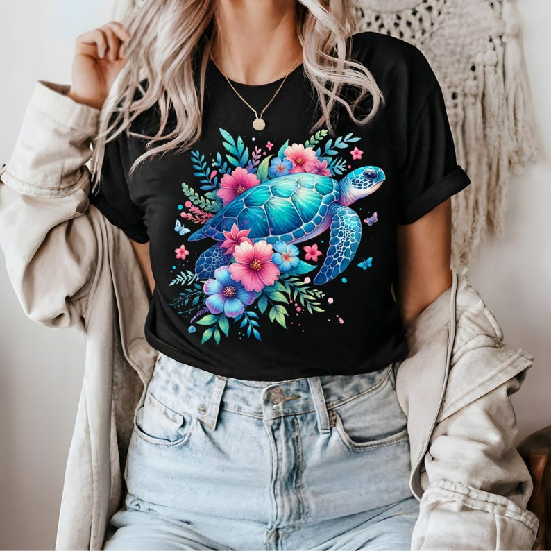 以下が含まれることがあります： 黒いTシャツ。鮮やかなウミガメのイラストが描かれており、カラフルな花と蝶が周りに描かれています。カメは青とターコイズ色の甲羅で、ピンクと青の花があります。デザインは詳細で目を引きます。