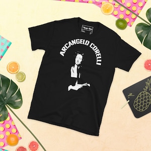 May include: Black t-shirt with a white graphic of a person with the text "Arcangelo Corelli" in a white arch.