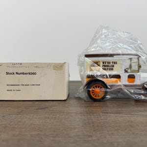 May include: A vintage-style toy van in a plastic wrapper, with orange wheels and accents, and the text "WE'RE THE PROBLEM SOLVERS". Beside it is a cardboard box with the text "Stock Number 9260".