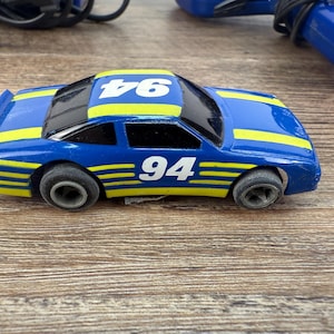 May include: Blue and yellow toy race car with the number 94 on the side.