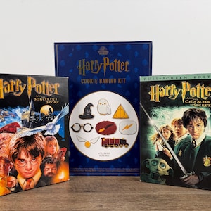 May include: Three Harry Potter themed items: two DVDs and a cookie baking kit. The DVDs are "Harry Potter and the Sorcerer's Stone" and "Harry Potter and the Chamber of Secrets". The cookie kit features a dark blue box with the words "Harry Potter Cookie Baking Kit".