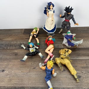 May include: A collection of anime figurines, including characters in various poses. The figures are brightly colored and detailed, with a variety of outfits and hairstyles. The figures are made of plastic and are displayed on a wooden surface.