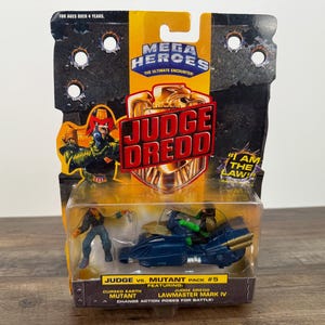 May include: A Judge Dredd action figure set in a plastic package. The package features the Mega Heroes logo and the words "Judge Dredd" in large letters. The set includes a Judge Dredd figure, a mutant figure, and a Lawmaster Mark IV vehicle.