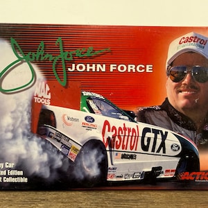 May include: A rectangular box featuring a graphic of a white Castrol GTX Funny Car with smoke, a portrait of John Force wearing a white Castrol cap and sunglasses, and the text John Force, Funny Car, Limited Edition, Adult Collectible.