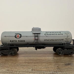 K&ouml;nnte beinhalten: Graues Diamond Chemicals Tankwagen-Modell mit schwarzen R&auml;dern und Fahrwerk. Der Tankwagen tr&auml;gt die Aufschrift "Diamond Chemicals" und "GATX 74225". Das Modell steht auf einer Holzoberfl&auml;che.