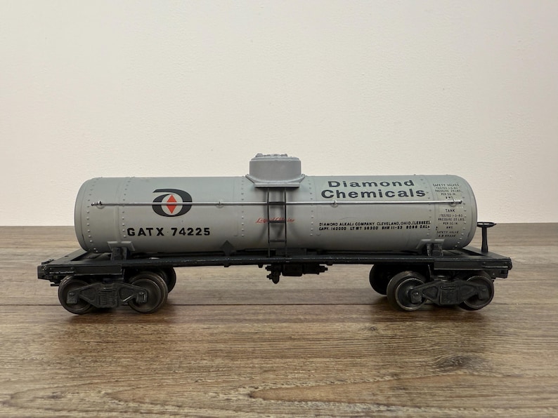 K&ouml;nnte beinhalten: Graues Diamond Chemicals Tankwagen-Modell mit schwarzen R&auml;dern und Fahrwerk. Der Tankwagen tr&auml;gt die Aufschrift "Diamond Chemicals" und "GATX 74225". Das Modell steht auf einer Holzoberfl&auml;che.