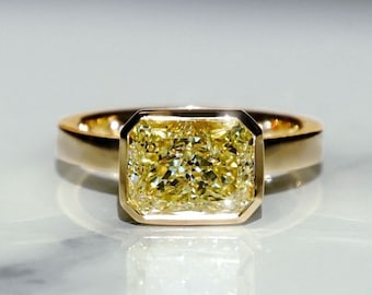 May include: A gold ring with a large, square-shaped, yellow diamond.