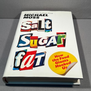 May include: A white book titled "Salt Sugar Fat: How the Food Giants Hooked Us" by Michael Moss, winner of the Pulitzer Prize. The title is in colourful, cut-out letters.