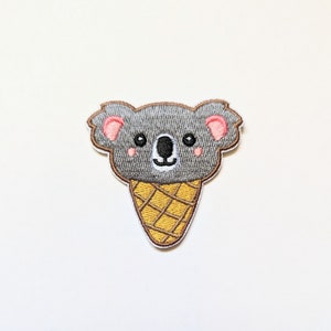 Puede incluir: Parche bordado para planchar de un koala gris que lleva un cono de helado. El koala tiene orejas rosas y una cara linda.