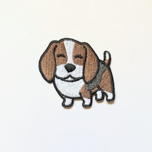 May include: Embroidered patch of a cartoon beagle dog. The patch features brown, white, and black colours. The dog has closed eyes and a happy expression. Suitable for clothing or accessories.