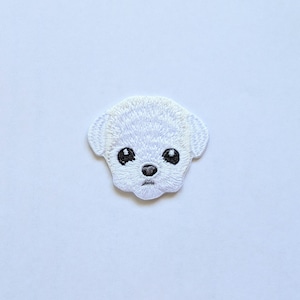 May include: White embroidered patch of a dog's face with black eyes and a black nose.