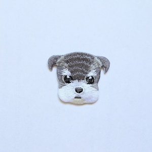 May include: Embroidered iron-on patch of a gray and white miniature schnauzer dog with a serious expression.