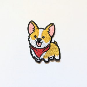 Könnte beinhalten: Gestickter Aufnäher eines Cartoon-Corgis mit einem roten Bandana. Der Corgi ist gelb mit weißen Markierungen und hat einen schwarzen Umriss.