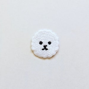 May include: White embroidered patch of a dog's face with black eyes and nose.