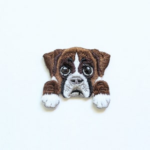 Könnte beinhalten: Gestickter Boxer-Hundeaufnäher mit braunem und weißem Fell, der das Gesicht und die Pfoten des Hundes zeigt. Der Aufnäher ist zum Aufbügeln oder Aufnähen auf Stoff geeignet, ideal für Tierliebhaber.