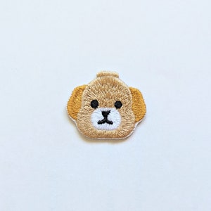 May include: Embroidered iron-on patch of a brown bear face with white nose and black eyes.