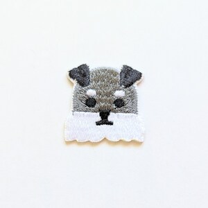 May include: Embroidered iron-on patch featuring a white and gray schnauzer dog with a fluffy beard.