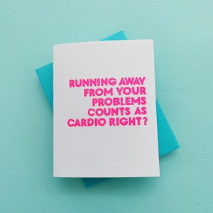 May include: A white card with pink text that reads "Running away from your problems counts as cardio right?"