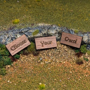 May include: Three wooden signs with the words "Choose", "Your", and "Own" engraved on them. The signs are arranged in a row on a grassy surface.