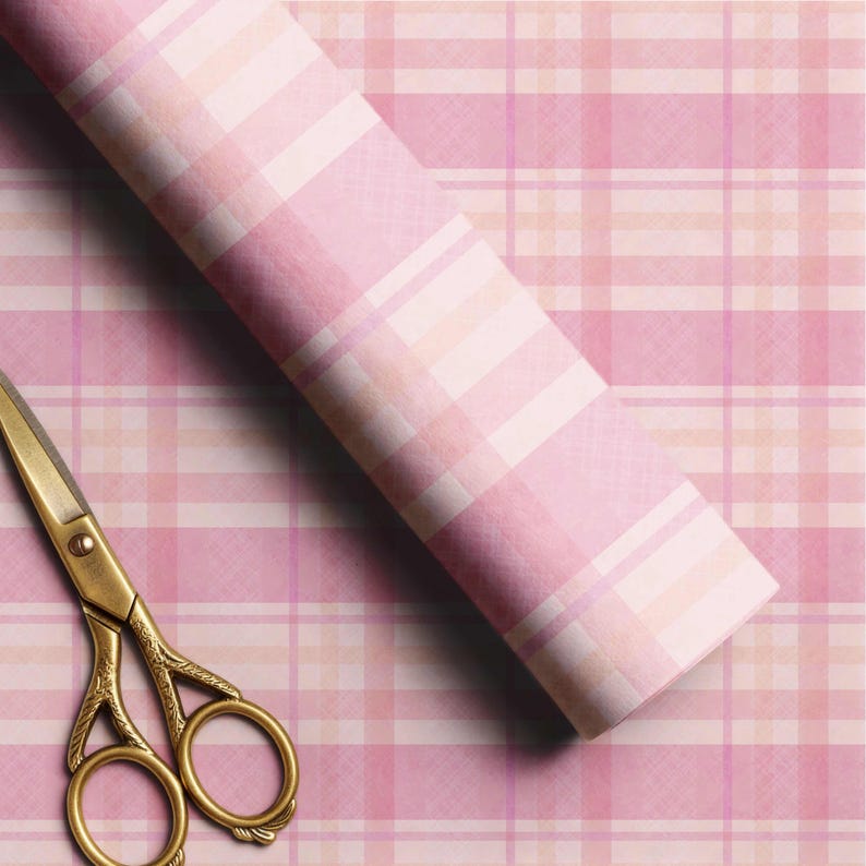 May include: A roll of wrapping paper featuring a pink, white, and light orange plaid pattern with a textured appearance, positioned diagonally across the frame next to a pair of ornate gold-colored metal scissors with intricate handle detailing.