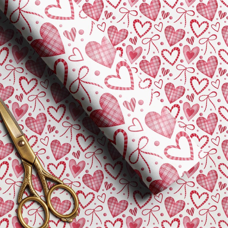 May include: A roll of white wrapping paper featuring a repeating pattern of red hearts and bows. Some hearts are solid red, while others have a red plaid texture. A pair of gold-colored metal scissors with ornate handles rests on the paper.