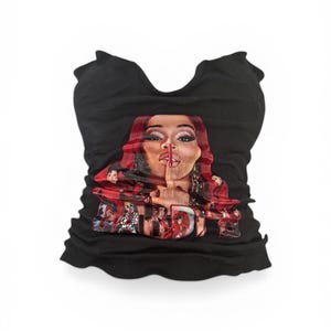 May include: Black tube top with a graphic of a woman's face with red hair and the word "Bardi" in red letters. The top is made of a ribbed material.