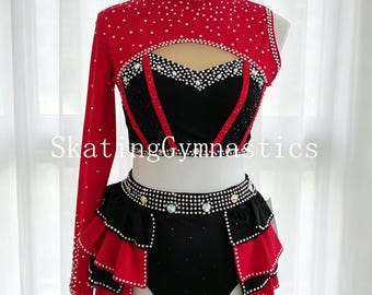 May include: Red and black skating or gymnastics outfit with rhinestone embellishments. The top has a high neck and one long sleeve. The skirt has a ruffled design. The text "Skating Gymnastics" is visible.