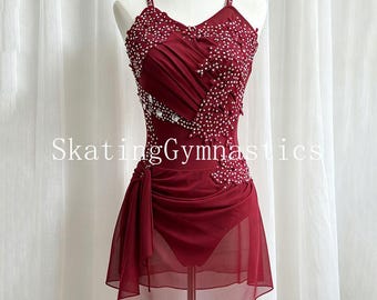 May include: A deep burgundy leotard with a sheer skirt overlay, featuring intricate white beadwork and crystal embellishments across the bodice and straps. The garment displays the text SkatingGymnastics across the center and has a ruched fabric design.