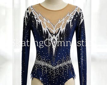 May include: A long-sleeved navy blue leotard featuring a nude-colored mesh neckline and chest panel. The garment is decorated with white jagged patterns and numerous clear crystals arranged in a gradient design across the front and sleeves.