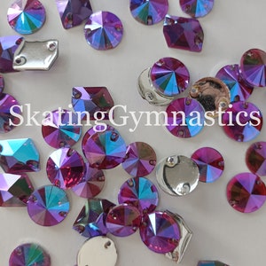 Puede incluir: Surtido de pedrería de color púrpura iridiscente y plata en varias formas y tamaños, incluyendo redondos, cuadrados y rectangulares. La pedrería está esparcida sobre una superficie blanca. El texto "Skating Gymnastics" es visible en el centro de la imagen.