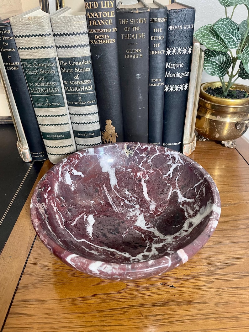 May include: A red and white marble bowl with a swirling pattern. The bowl is sitting on a wooden surface.