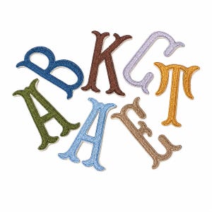 May include: A collection of seven embroidered letter patches in various colors including olive green, blue, brown, light purple, and gold. Each letter features a distinct serif typeface with a textured, stitched finish and a white border edge.