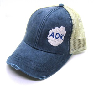 May include: A blue and beige distressed trucker hat with a white outline of the Adirondack Mountains and the text "ADK" in blue embroidery.