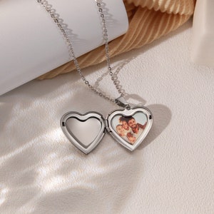 May include: A silver heart-shaped locket necklace with a photo of a family inside. The locket is open, revealing the photo.