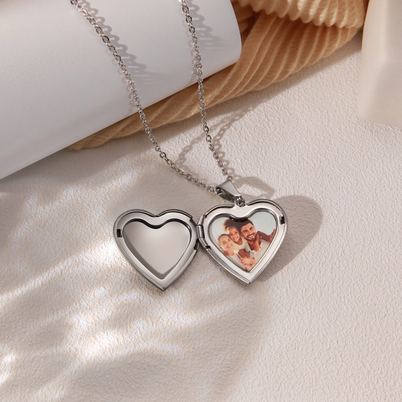 May include: A silver heart-shaped locket necklace with a photo of a family inside. The locket is open, revealing the photo.
