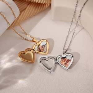 May include: Two heart-shaped locket necklaces, one gold and one silver, with photos inside. The lockets are open, revealing photos of people.