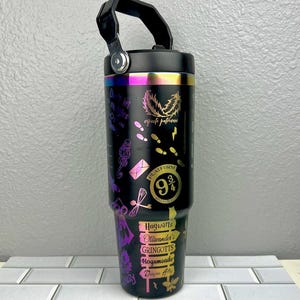 Puede incluir: Taza de viaje de acero inoxidable negro con asa negra y acabado arcoíris iridiscente. La taza presenta un tema de Harry Potter con gráficos del Expreso de Hogwarts, la Plataforma 9 3/4 y varias ubicaciones de Harry Potter.