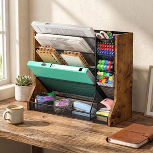 May include: A wooden desk organiser with multiple compartments and mesh dividers. It holds papers, a binder, pens, and other office supplies. The organiser has a rustic, distressed finish and is placed on a wooden desk with a cup of coffee and a succulent.