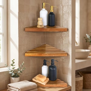 May include: Three triangular wooden corner shelves mounted on a tiled wall. The top shelf holds a white soap dispenser, a black soap dispenser, and a wooden brush. The bottom shelf holds a white soap dispenser, a black soap dispenser, and a bar of soap.