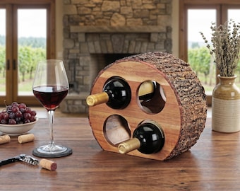 May include: A wooden wine rack with four bottle holders, crafted from a section of a tree trunk. The rack holds three wine bottles. A wine glass with red wine, a bowl of grapes, and a corkscrew are on the wooden table. A vase with dried flowers is in the background.