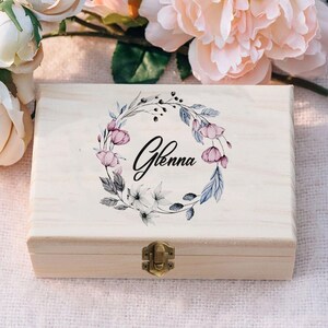 May include: A wooden box with a hinged lid and a brass latch. The lid is decorated with a watercolor floral wreath and the name "Glenna" in black script.