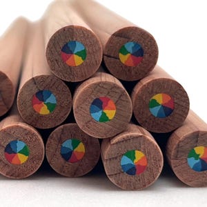 May include: A collection of round wooden pencils stacked together, each featuring a multi-colored core. The pencil leads are divided into six distinct segments, displaying a vibrant color wheel pattern of blue, green, yellow, orange, red, and purple.