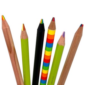 May include: Six sharpened pencils arranged in a fan shape. The pencils include two natural wood-toned pencils, two lime green pencils, one solid black pencil, and one pencil with horizontal rainbow stripes. Each pencil tip shows multi-colored lead.