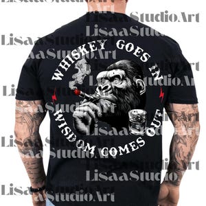 Op de afbeelding: Zwart t-shirt met een illustratie van een gorilla die een sigaar rookt en een glas whisky vasthoudt. De tekst luidt "Whiskey Goes In, Wisdom Comes Out". Rode bliksemgraphics zijn aanwezig. Een cool ontwerp voor een casual look.