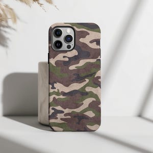 May include: A camouflage phone case with a green, brown, and beige pattern. The case has a cutout for the camera lens.